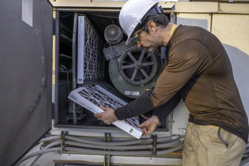 HVAC mechanic changing filters on a commercial ventilation system